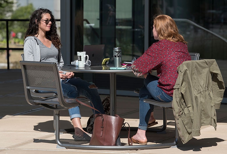 Two students sitting a table outside on 91's campus.