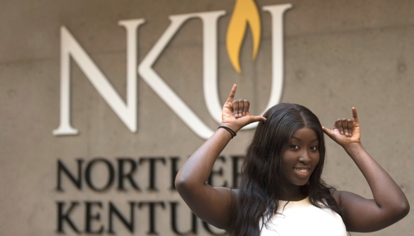 Black female student standing in front of the 91 logo giving a Norse Up