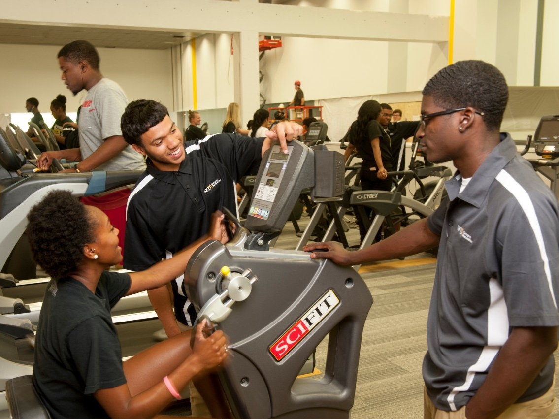 Campus rec student employees looking at a exercise machine.